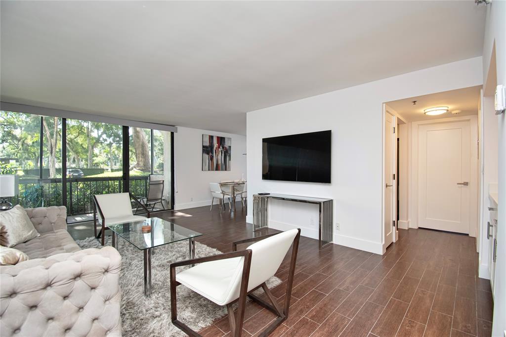 1612 Bridgewood Drive, Unit 1612 Boca Raton, FL 33434 - Photo 6 of 38 a living room with furniture a flat screen tv and a floor to ceiling window