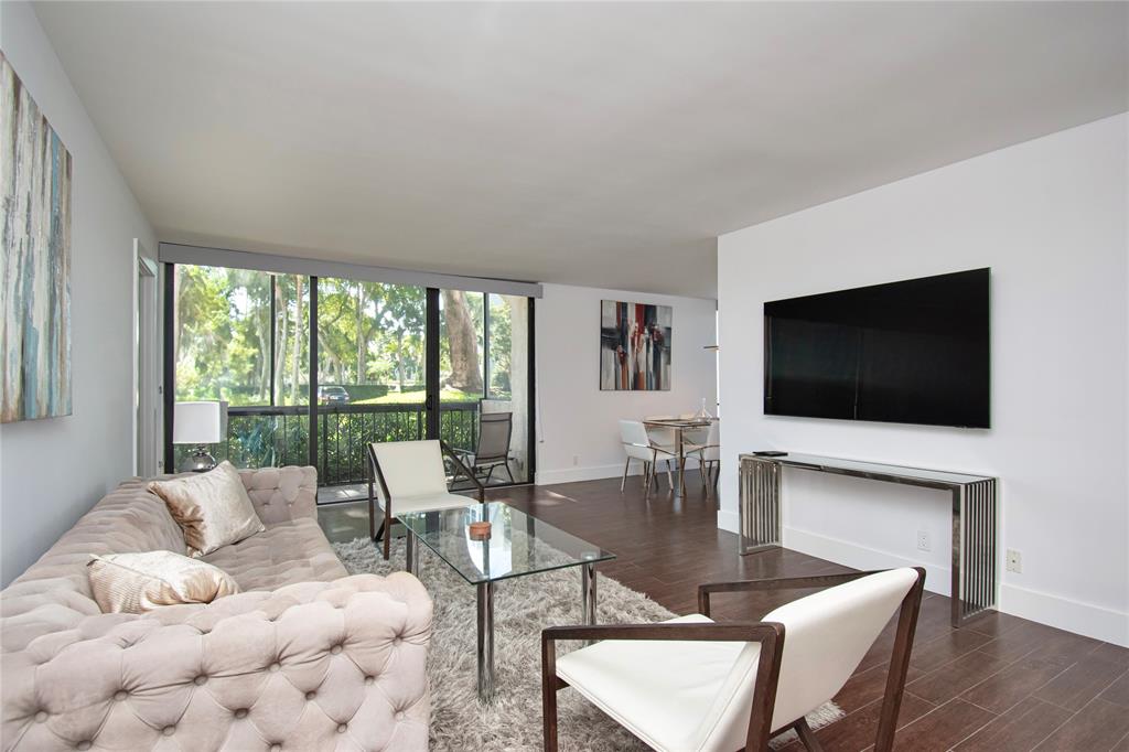 1612 Bridgewood Drive, Unit 1612 Boca Raton, FL 33434 - Photo 7 of 38 a living room with furniture a flat screen tv and a large window