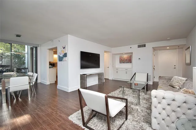 a living room with furniture a flat screen tv and a floor to ceiling window