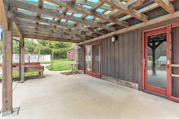 a view of a porch with wooden floor and roof with a garden view