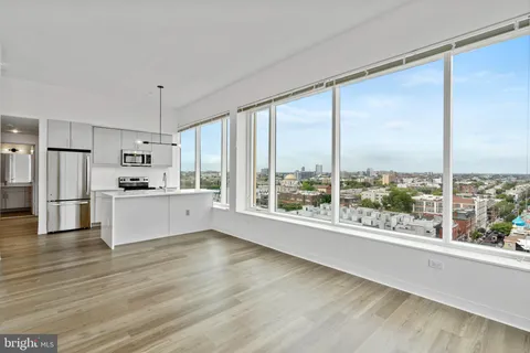a view of kitchen with stainless steel appliances wooden floor and large window