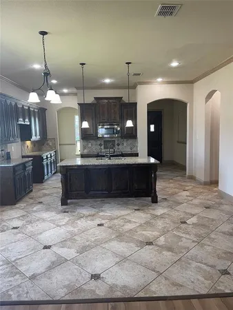 a large kitchen with kitchen island granite countertop a table and chairs in it