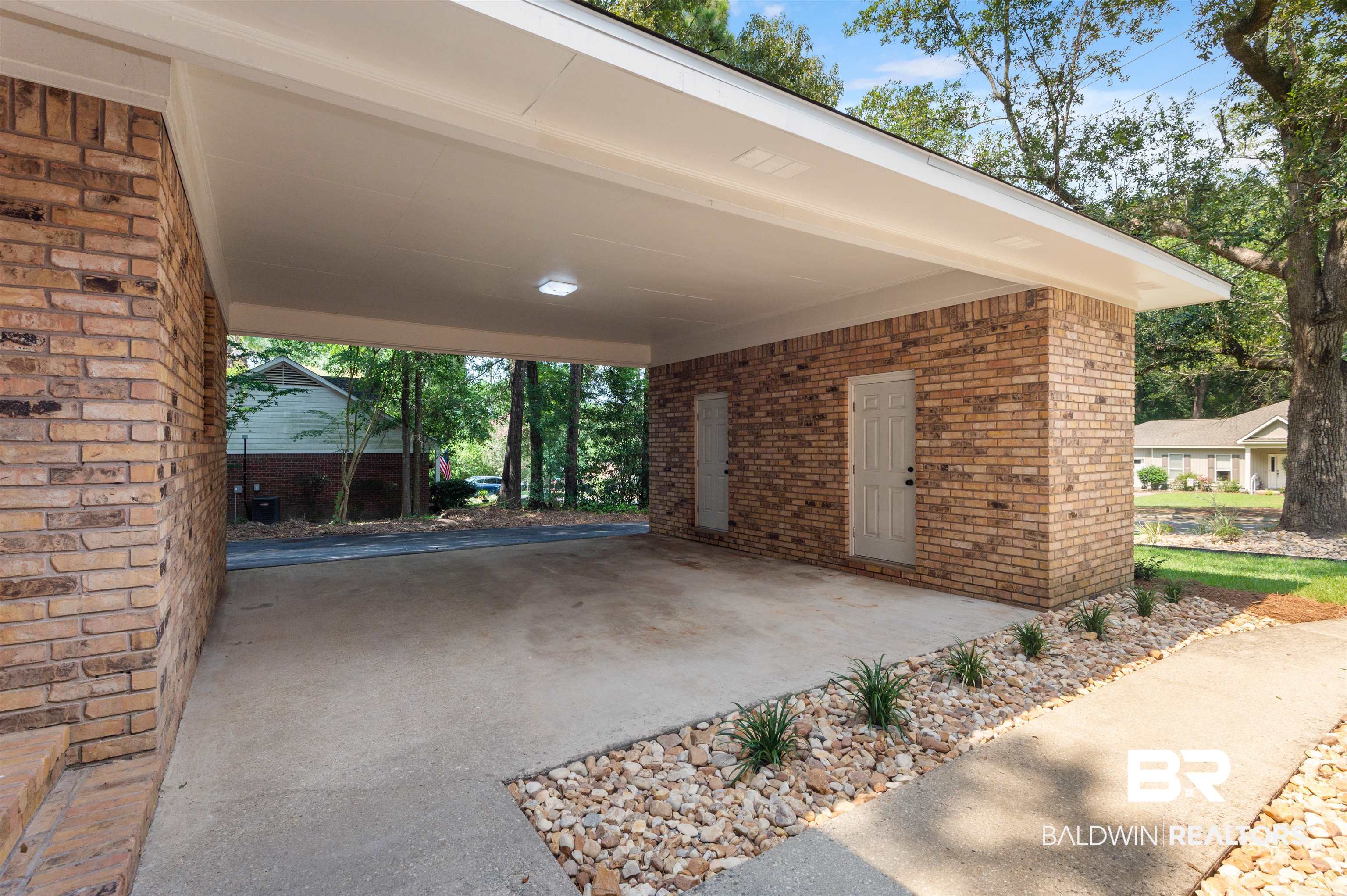 599 Ridgewood Drive Daphne, AL 36526 - Photo 27 of 41 Brick carport featuring a concrete slab, recessed lighting, two storage doors, and a decorative rock and plant bed