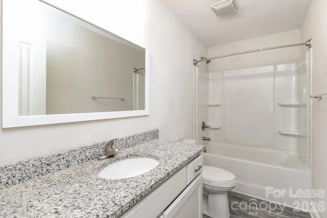 a bathroom with a granite countertop sink toilet mirror and shower