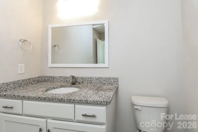 a bathroom with a granite countertop toilet sink and mirror