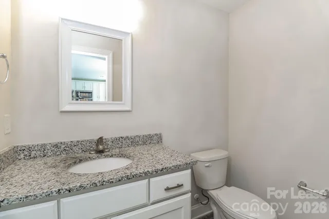 a bathroom with a granite countertop toilet and a sink
