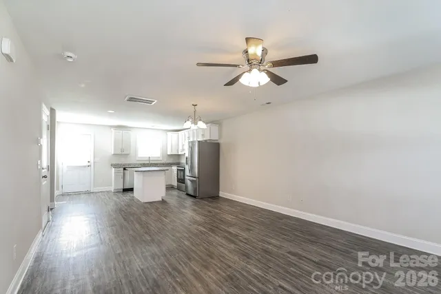 a view of a room with wooden floor a ceiling fan and window