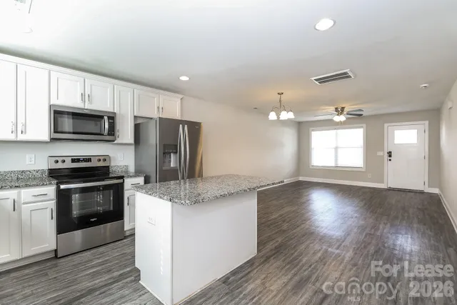 a kitchen with stainless steel appliances granite countertop a sink a stove a refrigerator cabinets and wooden floor