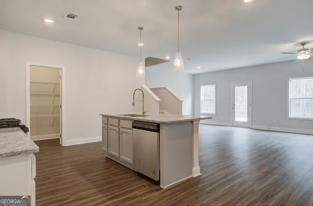a kitchen with stainless steel appliances granite countertop a sink a stove and a wooden floors