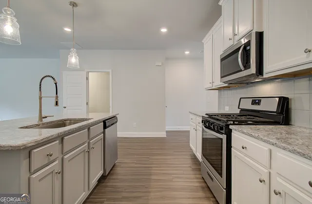 a kitchen with stainless steel appliances granite countertop a sink a stove top oven and wooden floors