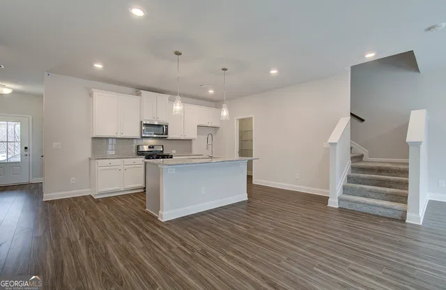 a kitchen with wooden floors stainless steel appliances and white cabinets