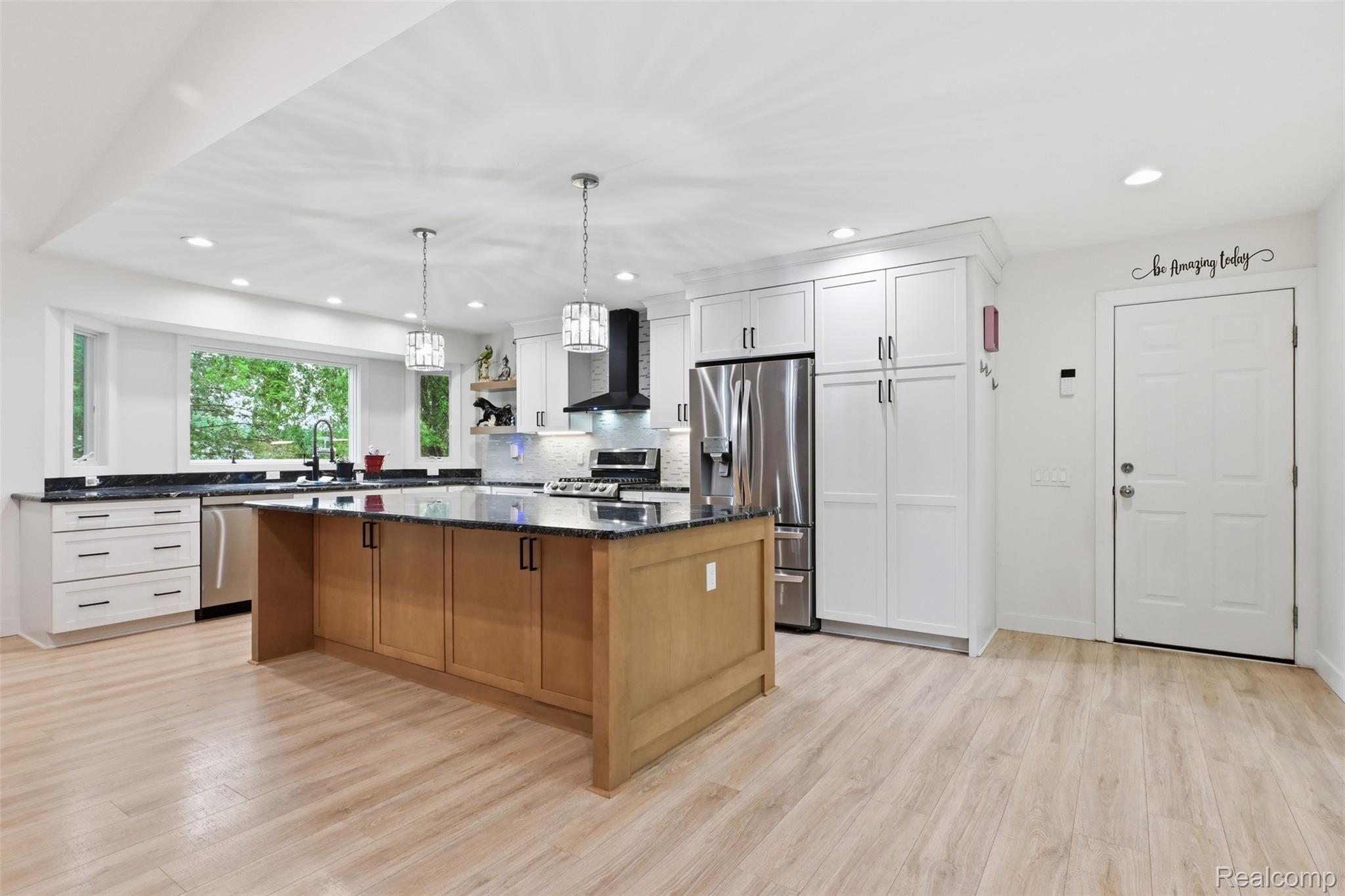 45738 Bemis Road Belleville, MI 48111 - Photo 13 of 52 Bright kitchen featuring luxury vinyl plank flooring, a large central island with dark countertops, white upper and lower cabinetry, stainless steel appliances, and recessed lighting