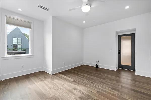 a view of an empty room with wooden floor and a window