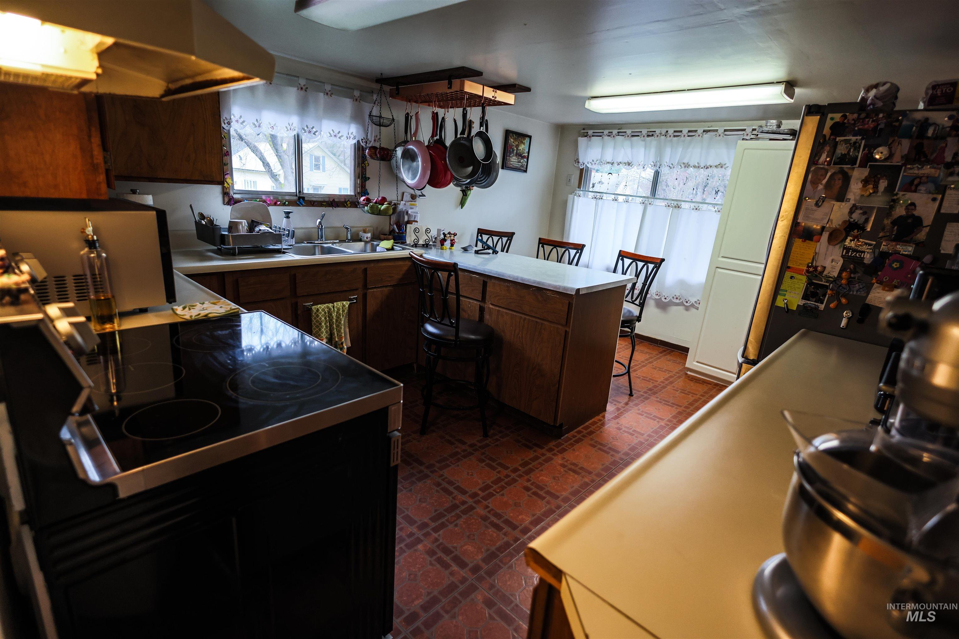 712 Hill Street Kamiah, ID 83536 - Photo 12 of 41 Kitchen featuring a peninsula, dark floors, black range with electric stovetop, light countertops, and dark wood finish cabinetry