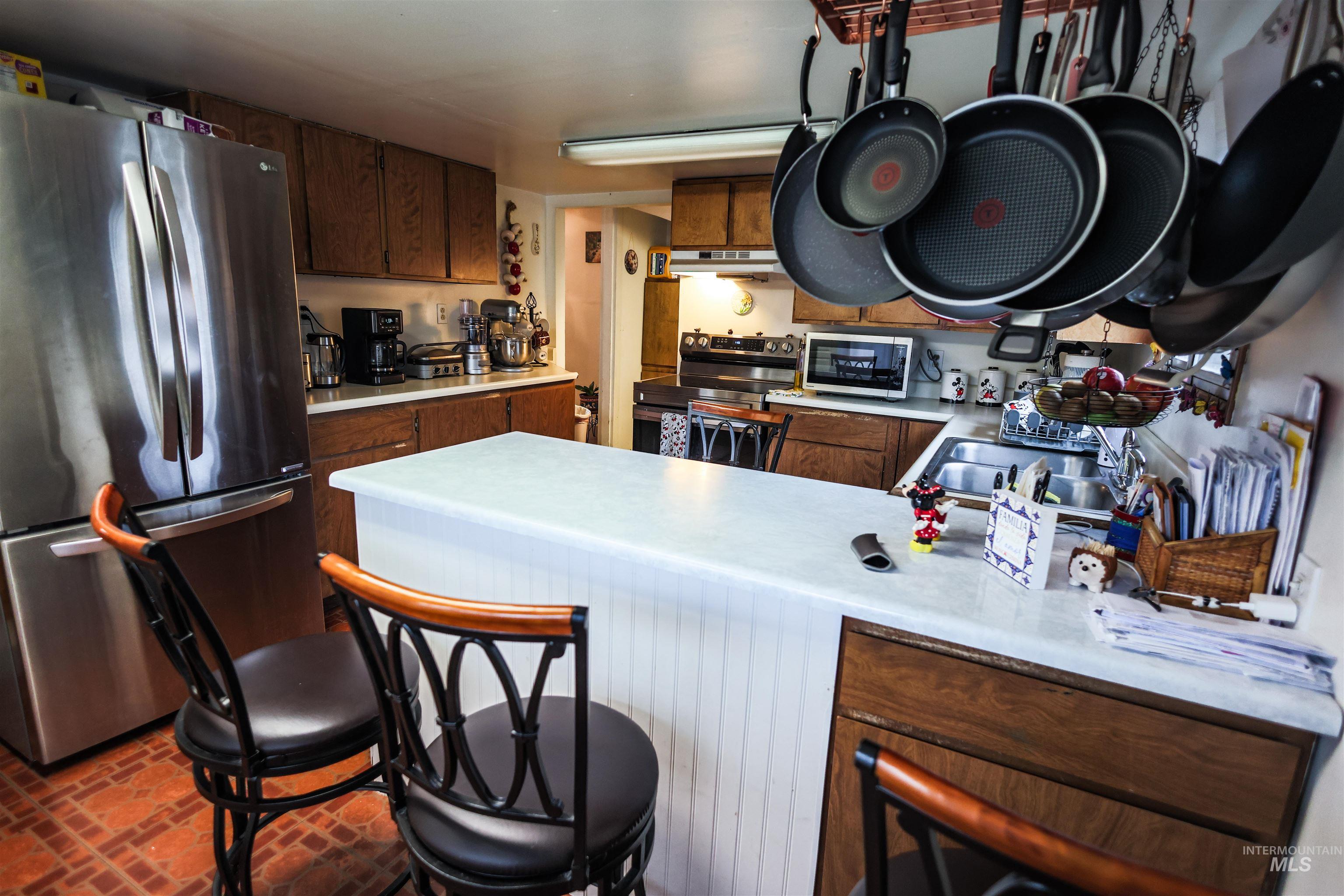 712 Hill Street Kamiah, ID 83536 - Photo 14 of 41 Kitchen with stainless steel appliances, light countertops, a peninsula, wood finish cabinetry, and a kitchen bar
