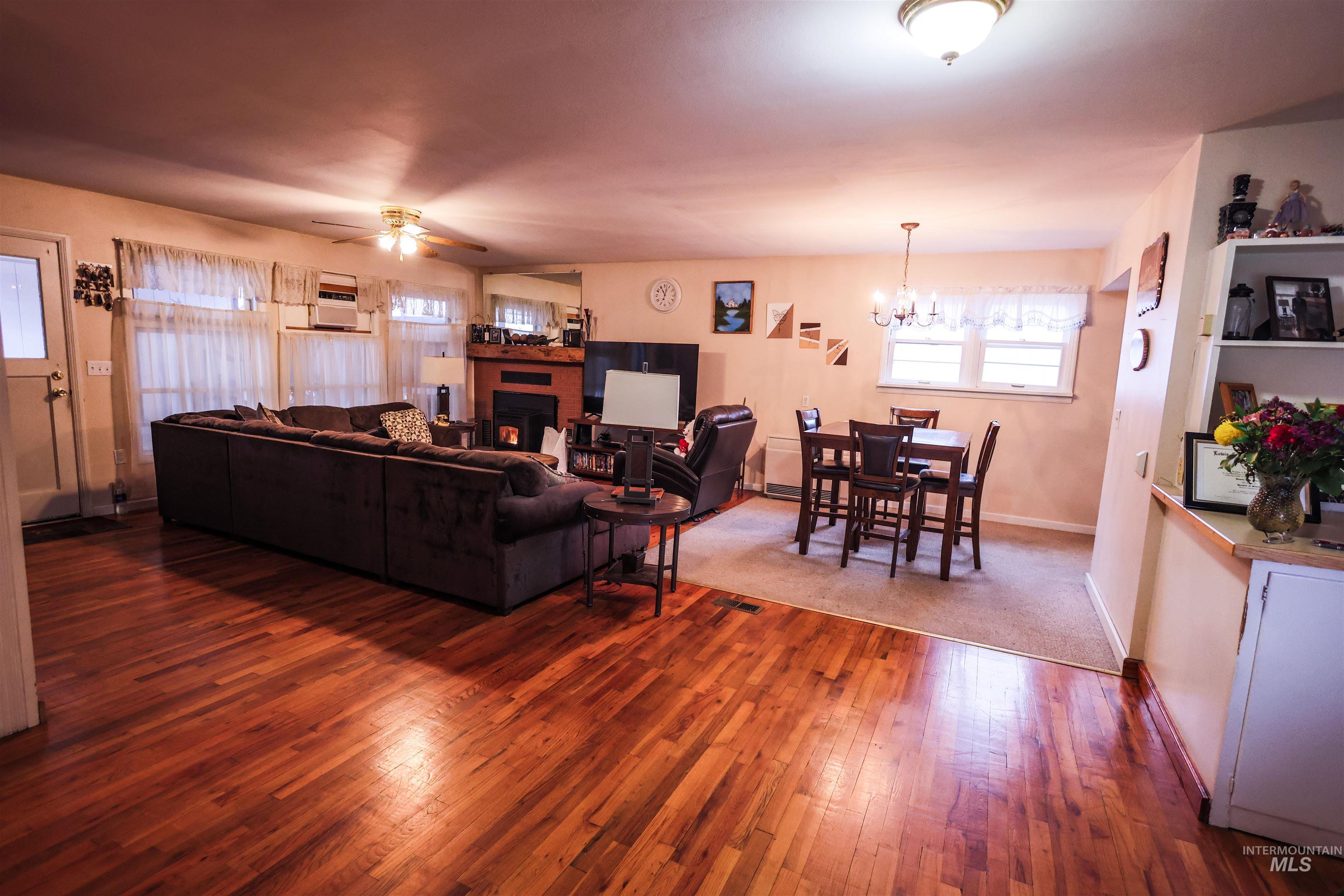 712 Hill Street Kamiah, ID 83536 - Photo 18 of 41 Living room with a ceiling fan, hardwood / wood-style floors, a chandelier, and a fireplace