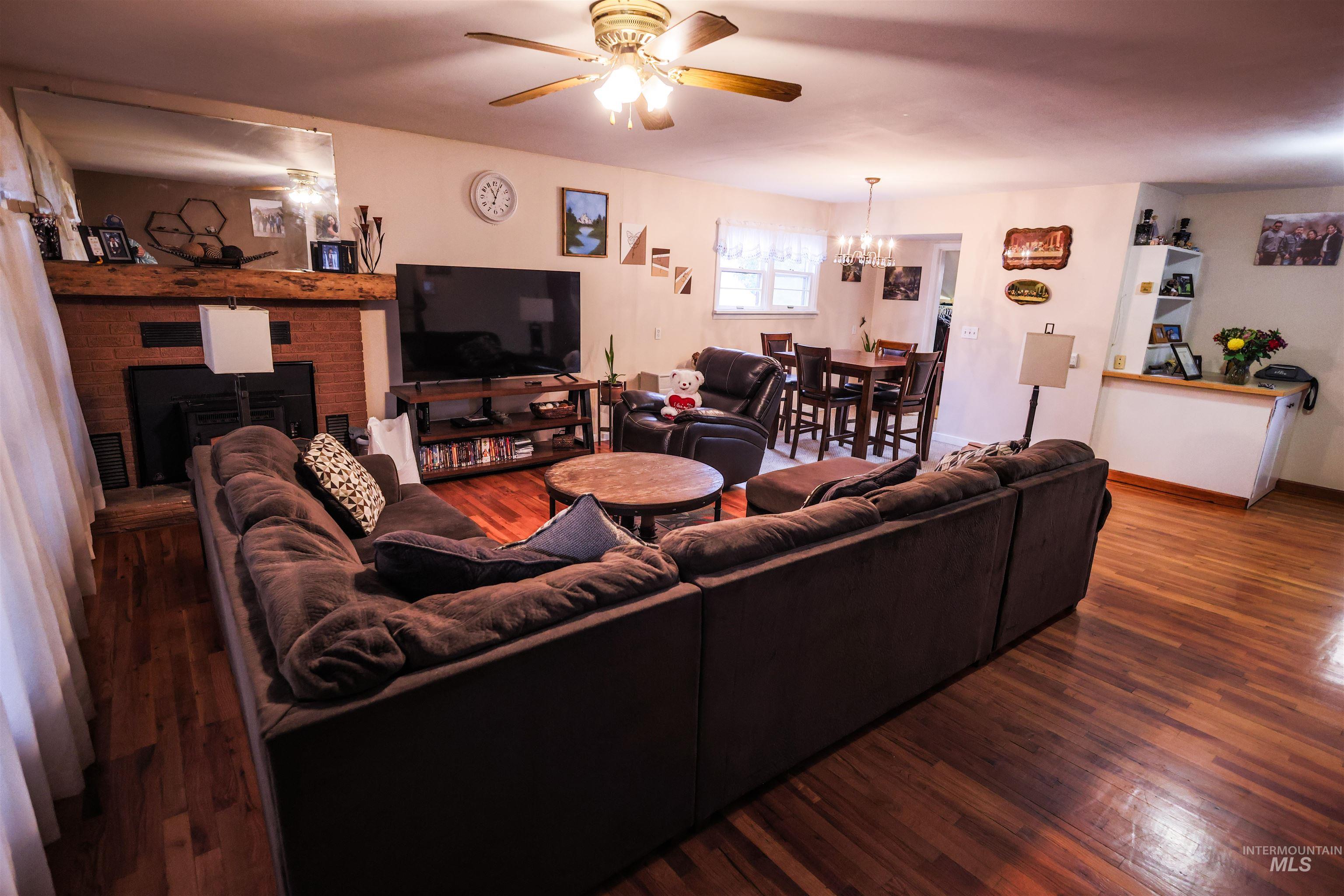 712 Hill Street Kamiah, ID 83536 - Photo 19 of 41 Living area featuring a ceiling fan, wood finished floors, a brick fireplace, and suspended lighting