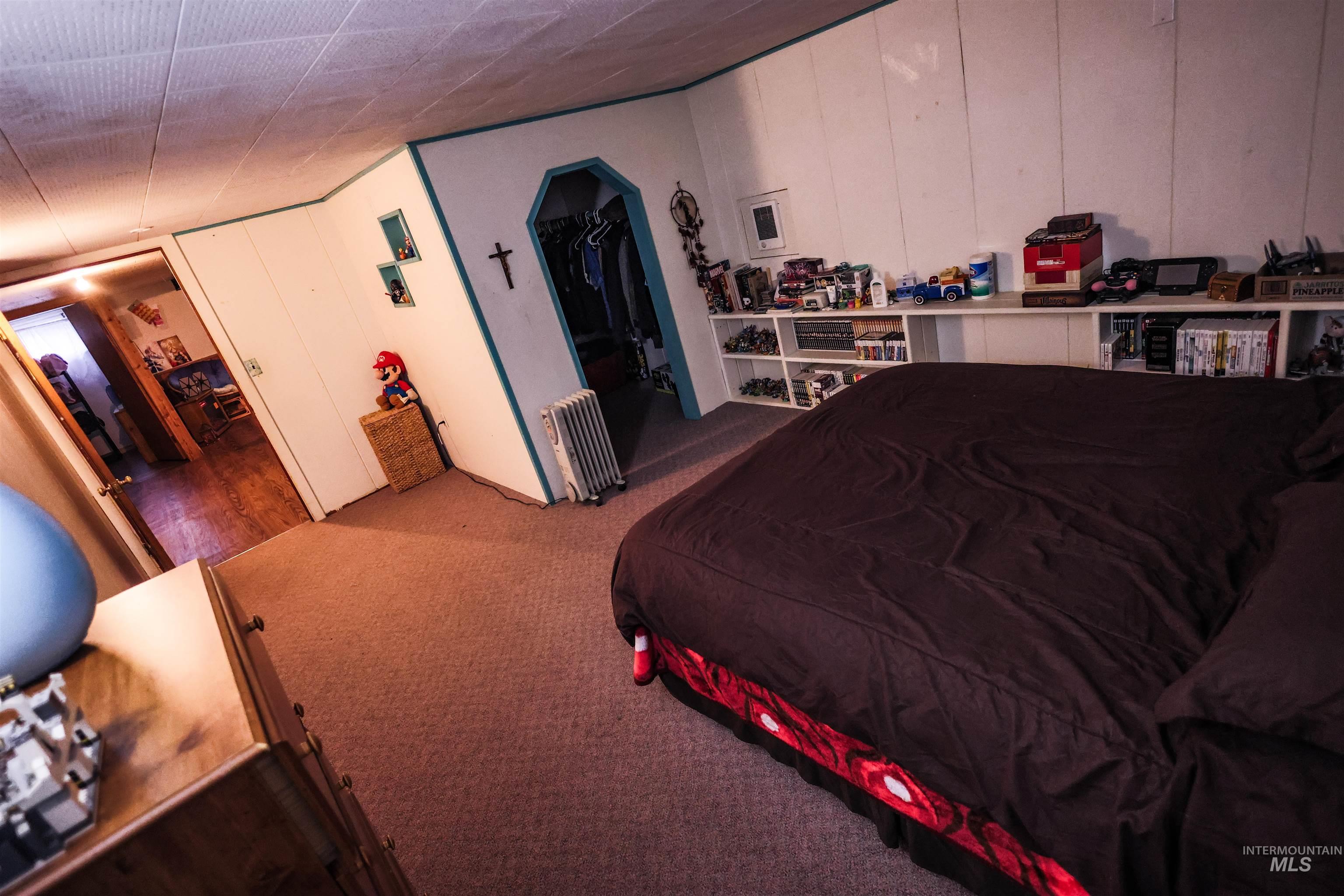 712 Hill Street Kamiah, ID 83536 - Photo 33 of 41 Bedroom with a closet, radiator heating unit, a decorative wall, and carpet floors