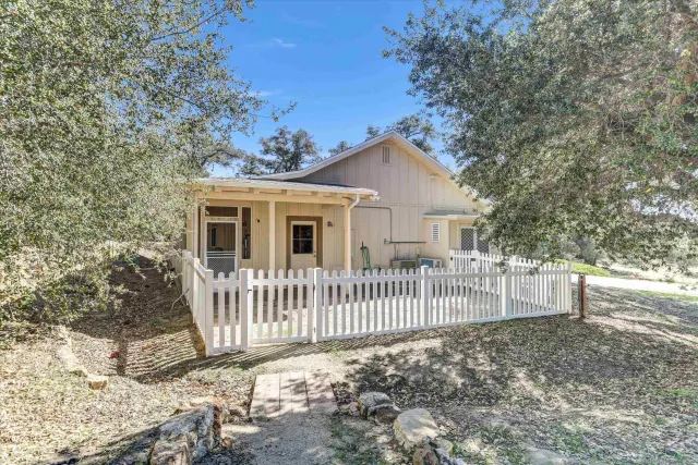 a view of a house with a small yard and wooden fence