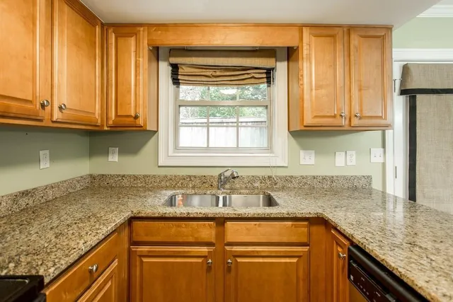a kitchen with granite countertop cabinets sink and window