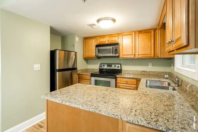 a kitchen with stainless steel appliances granite countertop a refrigerator a stove top oven a sink and dishwasher