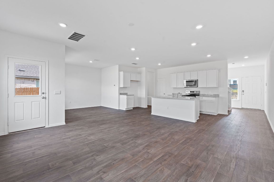18500 B Empire Path Manor, TX 78653 - Photo 11 of 31 Unfurnished living room featuring healthy amount of natural light, dark wood-style flooring, and recessed lighting
