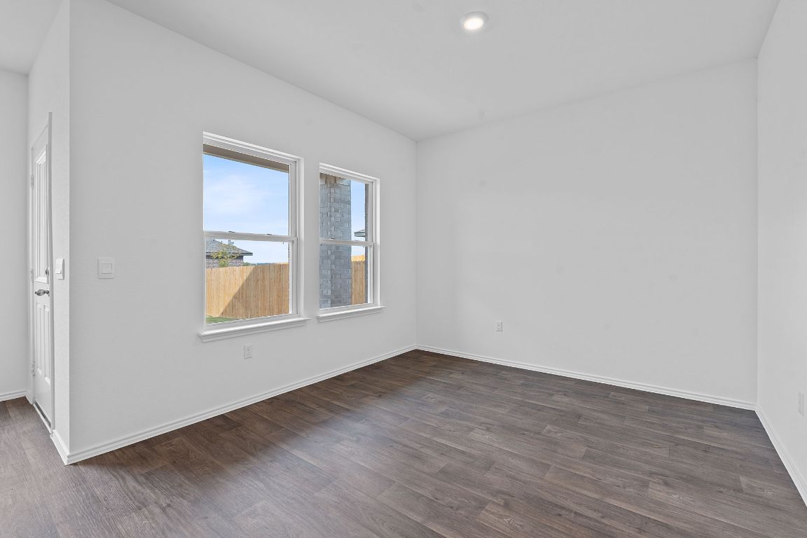 18500 B Empire Path Manor, TX 78653 - Photo 14 of 31 Empty room with dark wood-style floors and recessed lighting