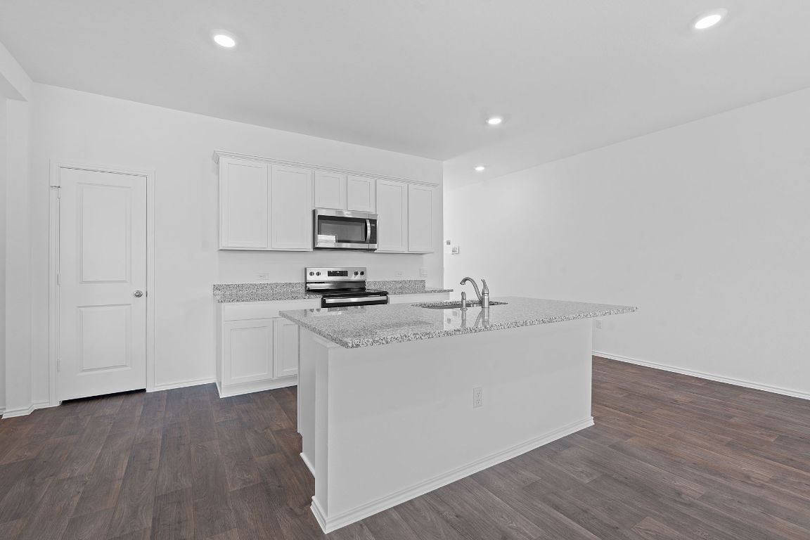 18500 B Empire Path Manor, TX 78653 - Photo 15 of 31 Kitchen with white cabinetry, stainless steel appliances, light stone counters, dark wood-type flooring, and recessed lighting