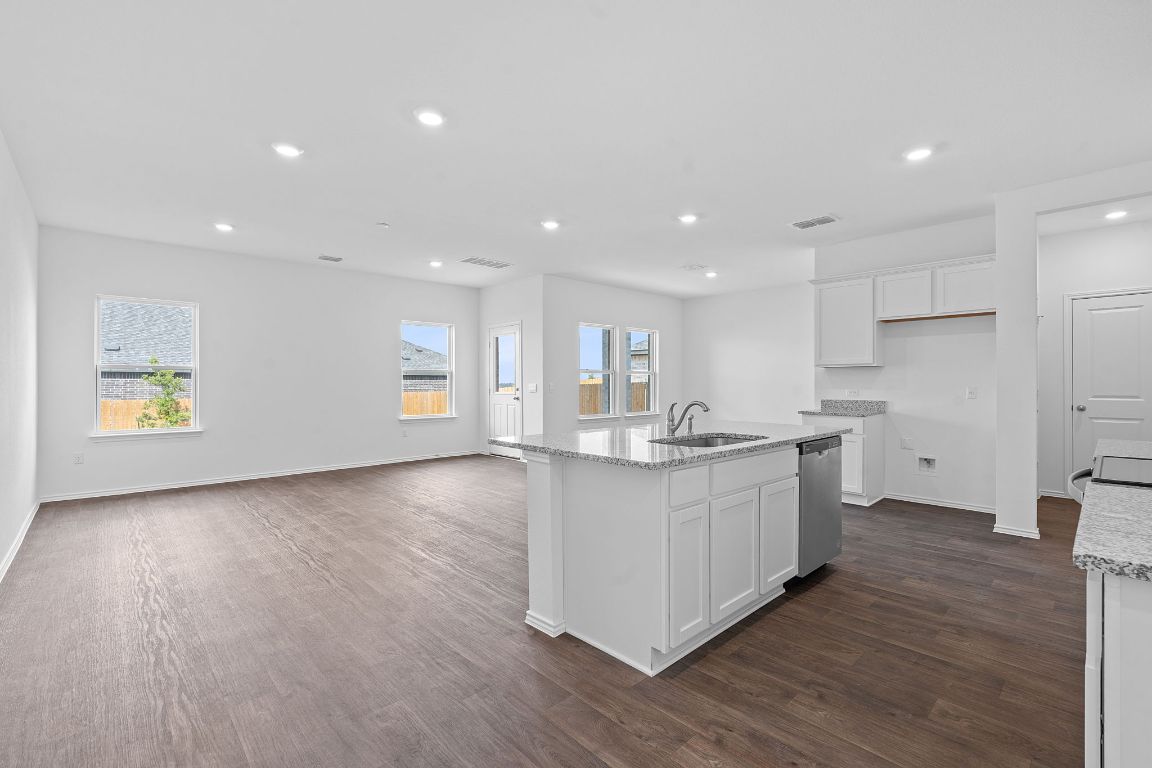 18500 B Empire Path Manor, TX 78653 - Photo 17 of 31 Kitchen with white cabinets, recessed lighting, light stone counters, dark wood finished floors, and an island with sink
