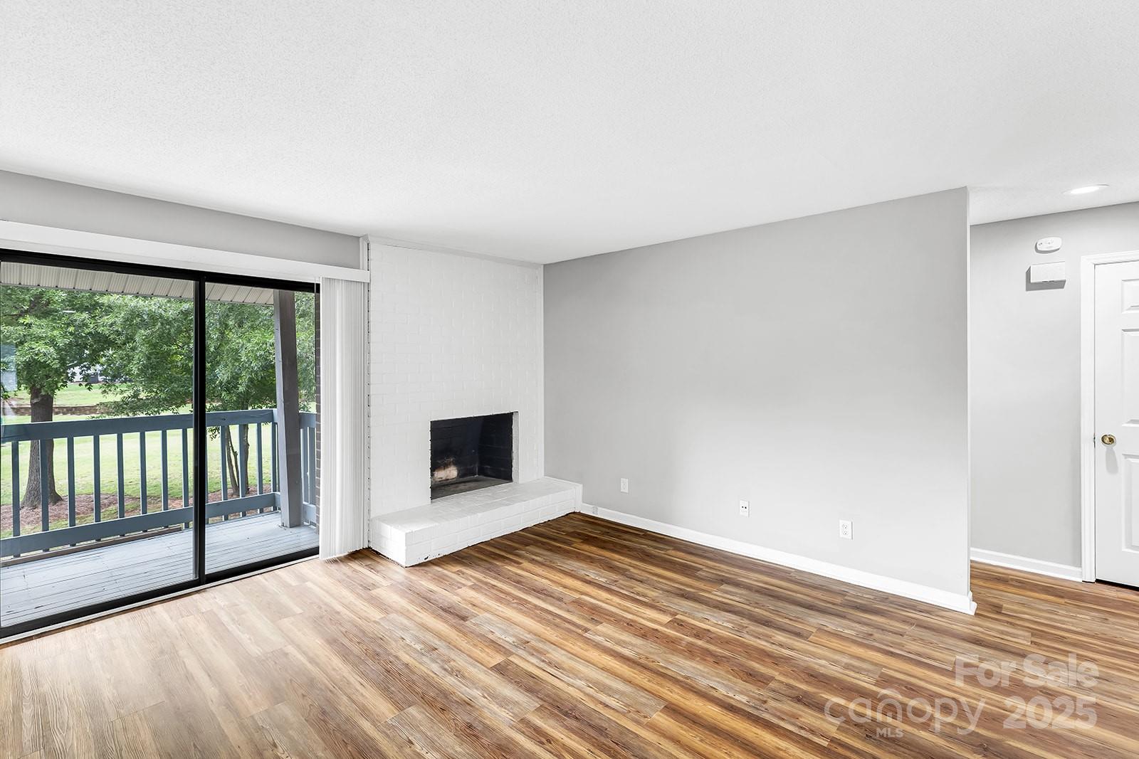 11015 Harrowfield Road Charlotte, NC 28226 - Photo 3 of 28 a view of empty room with wooden floor and fireplace