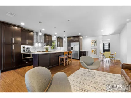 a kitchen with stainless steel appliances kitchen island granite countertop a refrigerator a stove a sink dishwasher with a dining table and chairs with wooden floor