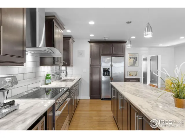 a kitchen with granite countertop a refrigerator a sink a stove and wooden cabinets