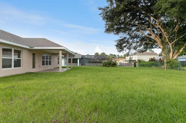 a view of a yard in front of a house with a large tree