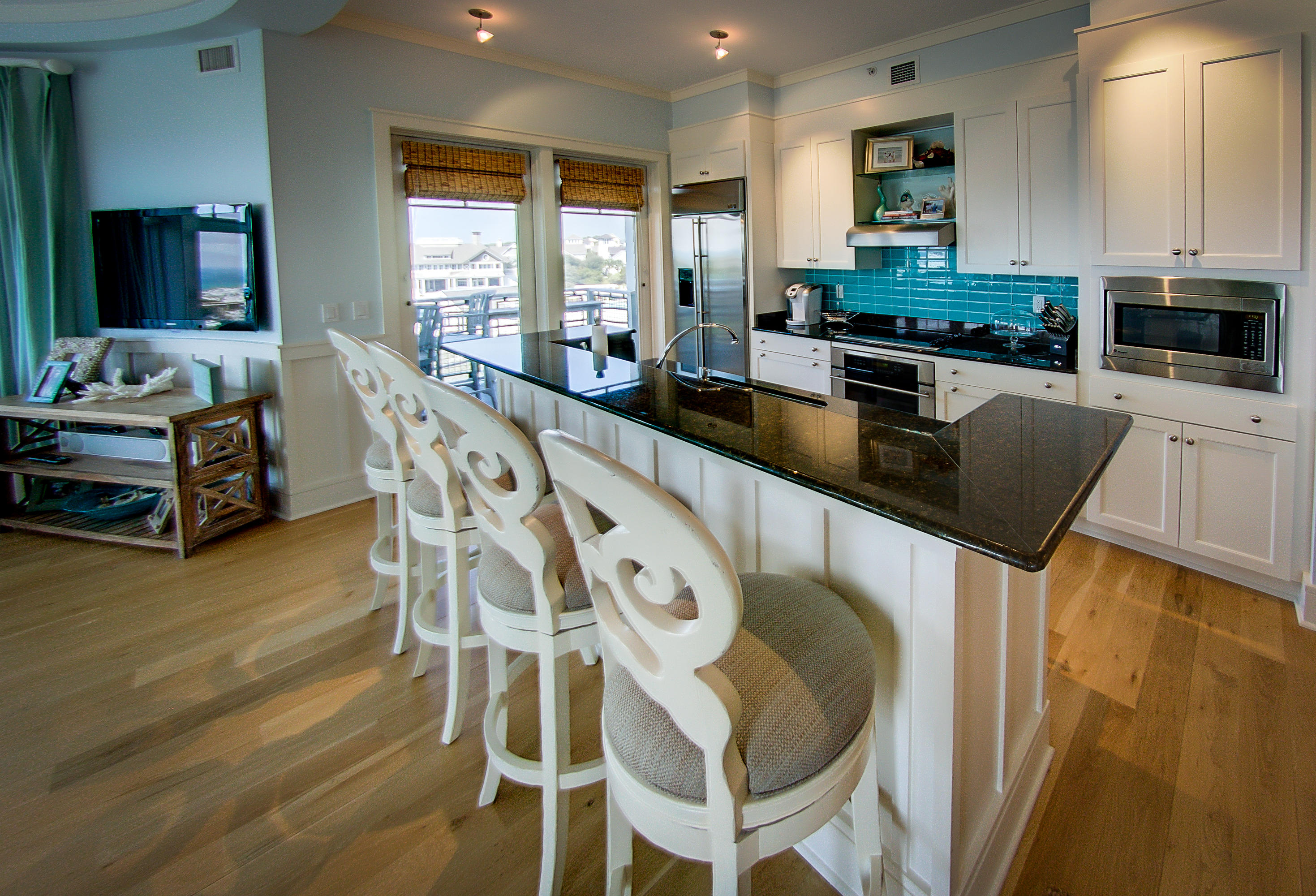 99 Compass Point Way Inlet Beach, Unit 308 Inlet Beach, FL 32461 - Photo 15 of 55 a kitchen with stainless steel appliances granite countertop a stove a sink a microwave a dining table and chairs with wooden floor