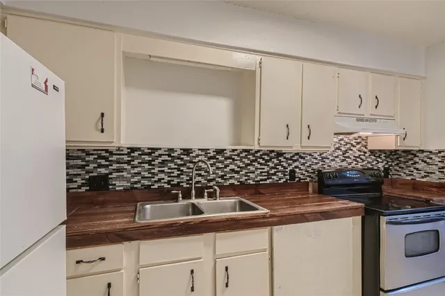 a kitchen with granite countertop white cabinets and black appliances
