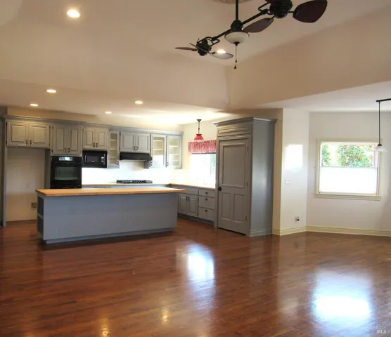 a large kitchen with stainless steel appliances wooden floors and large window