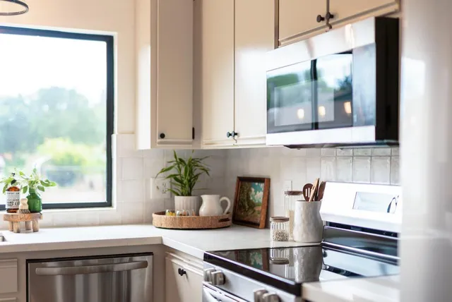 a kitchen with stainless steel appliances granite countertop a sink a stove a refrigerator and white cabinets with wooden floor