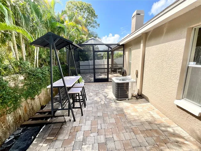 a view of a patio with a dining table and chairs under an umbrella with a small yard