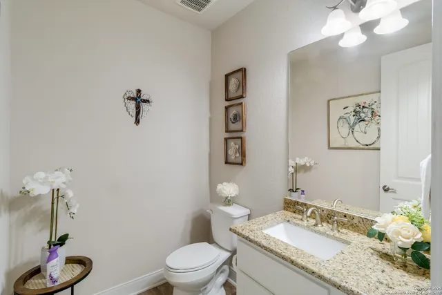 a bathroom with a granite countertop sink a toilet and a mirror