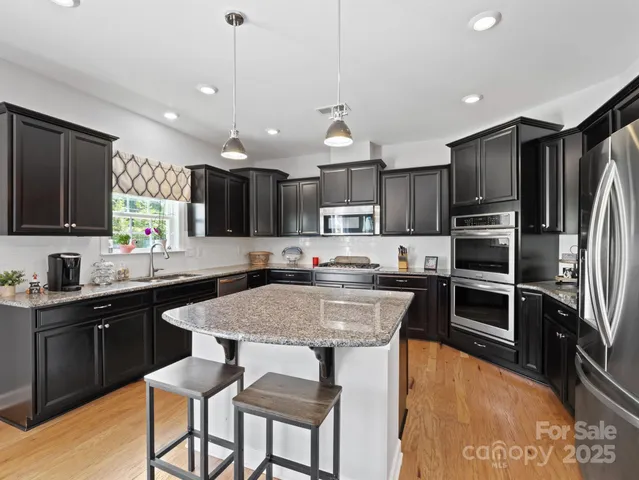 a kitchen with kitchen island granite countertop a sink and stainless steel appliances