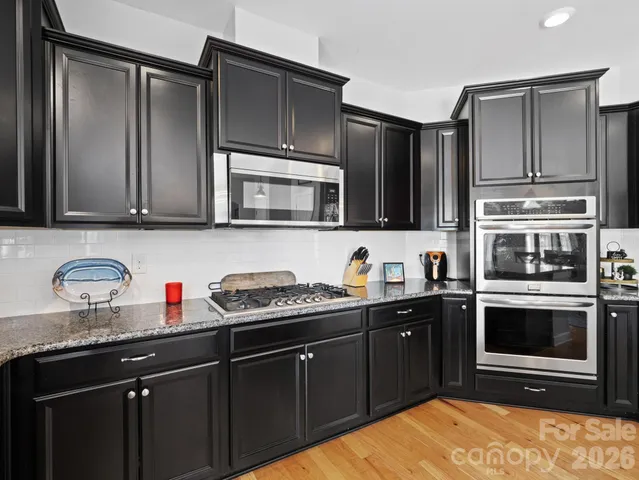 a kitchen with stainless steel appliances granite countertop a stove microwave and sink
