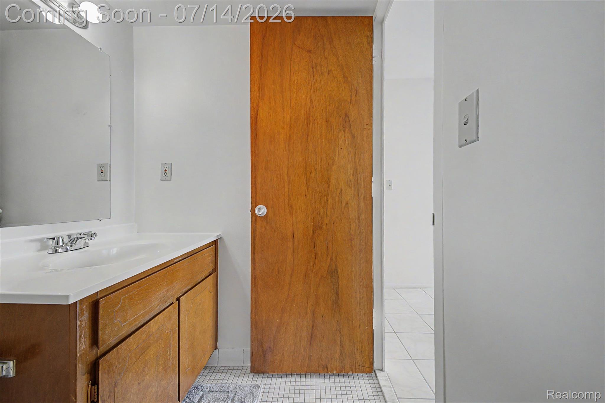 22700 Garrison Street, Unit 707 Dearborn, MI 48124 - Photo 17 of 22 Bathroom vanity featuring a white countertop and integrated sink, chrome faucet, wood-finish cabinetry, and an overhead vanity light bar