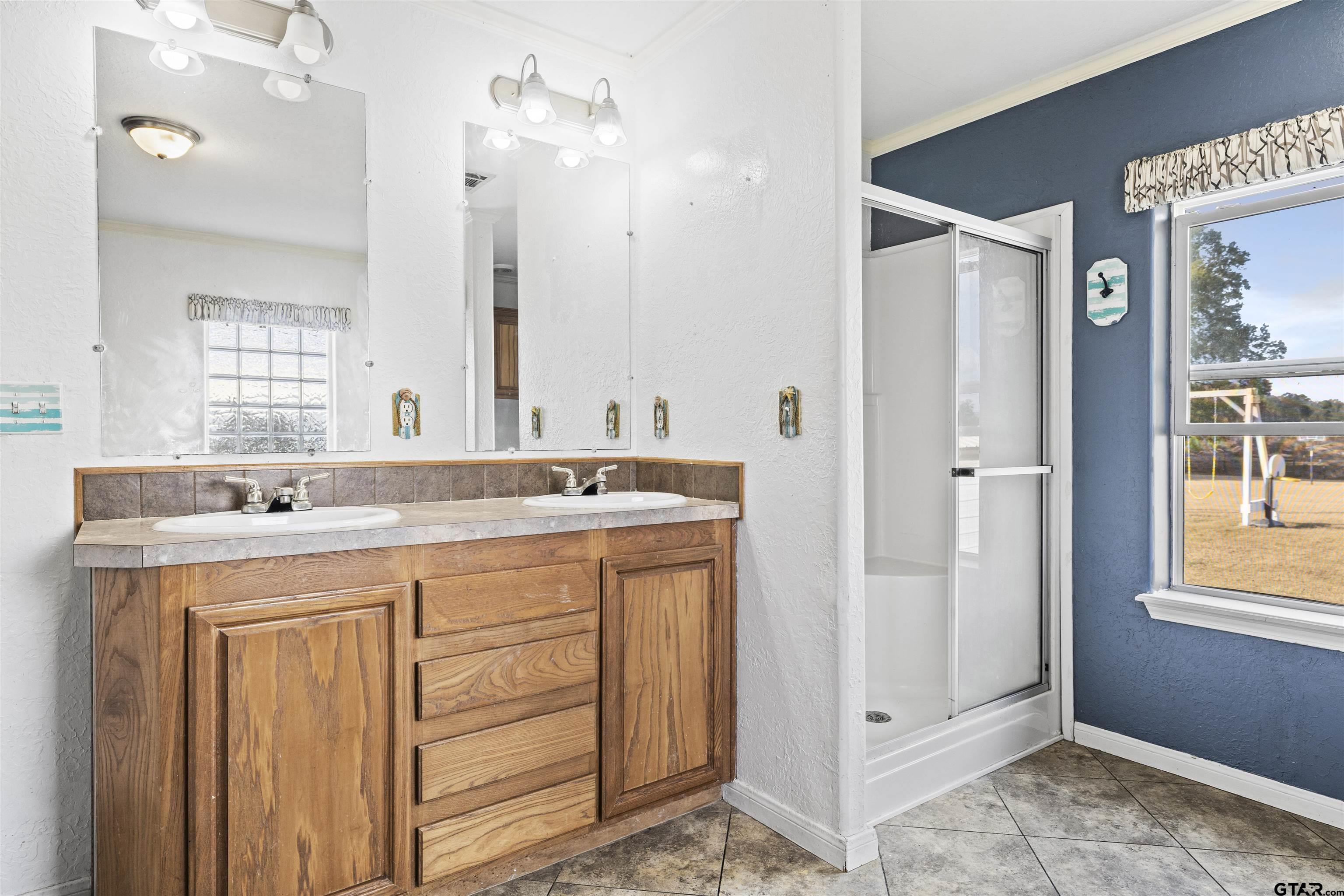 2089 Cottonwood Road Gilmer, TX 75645 - Photo 17 of 30 a bathroom with a double vanity sink a mirror and a shower