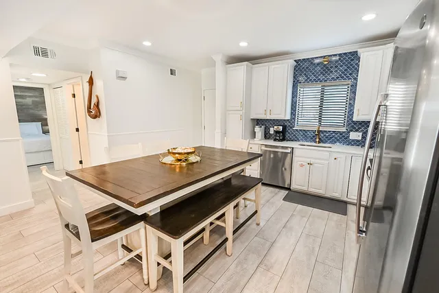 a kitchen with stainless steel appliances a stove a sink dishwasher a refrigerator white cabinets and wooden floor