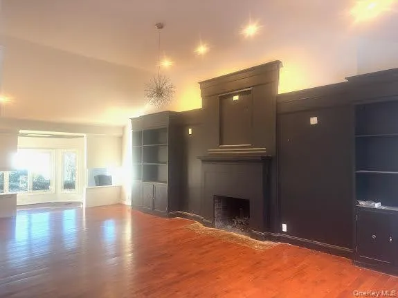 a view of an empty room with wooden floor and a fireplace