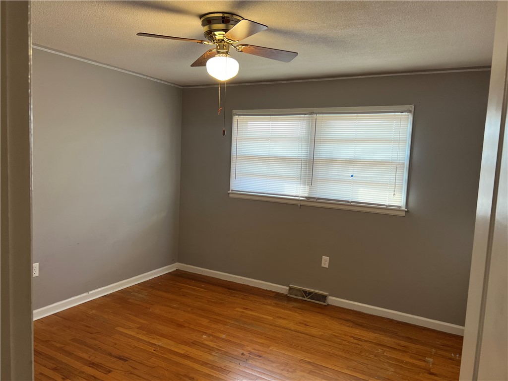 106 Donhill Road Anderson, SC 29625 - Photo 5 of 11 This cozy bedroom features warm hardwood flooring and a functional ceiling fan for comfort.