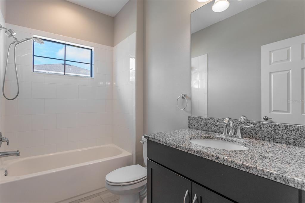 6906 Paradiso Drive Apollo Beach, FL 33572 - Photo 13 of 37 a bathroom with a granite countertop sink a toilet and shower