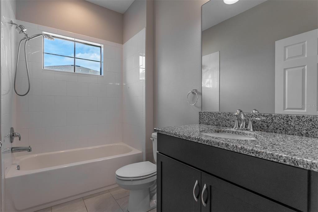 6906 Paradiso Drive Apollo Beach, FL 33572 - Photo 16 of 37 a bathroom with a granite countertop sink a toilet and bathtub