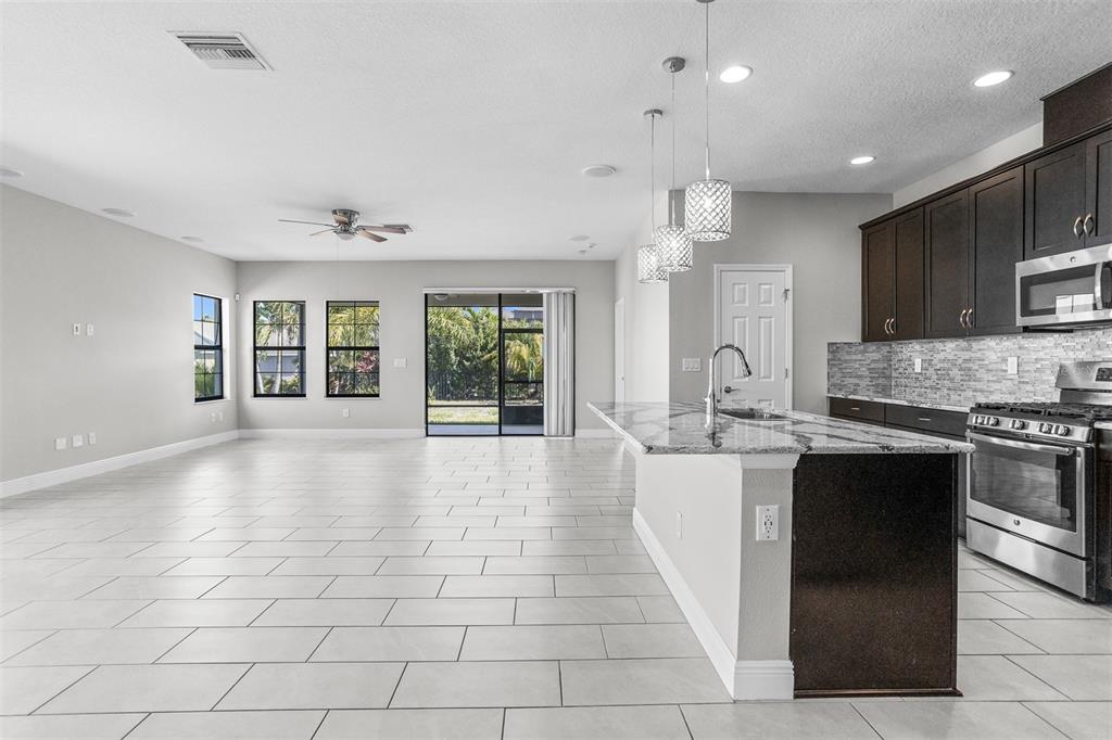 6906 Paradiso Drive Apollo Beach, FL 33572 - Photo 5 of 37 a large kitchen with kitchen island granite countertop a stove a sink a counter space and cabinets