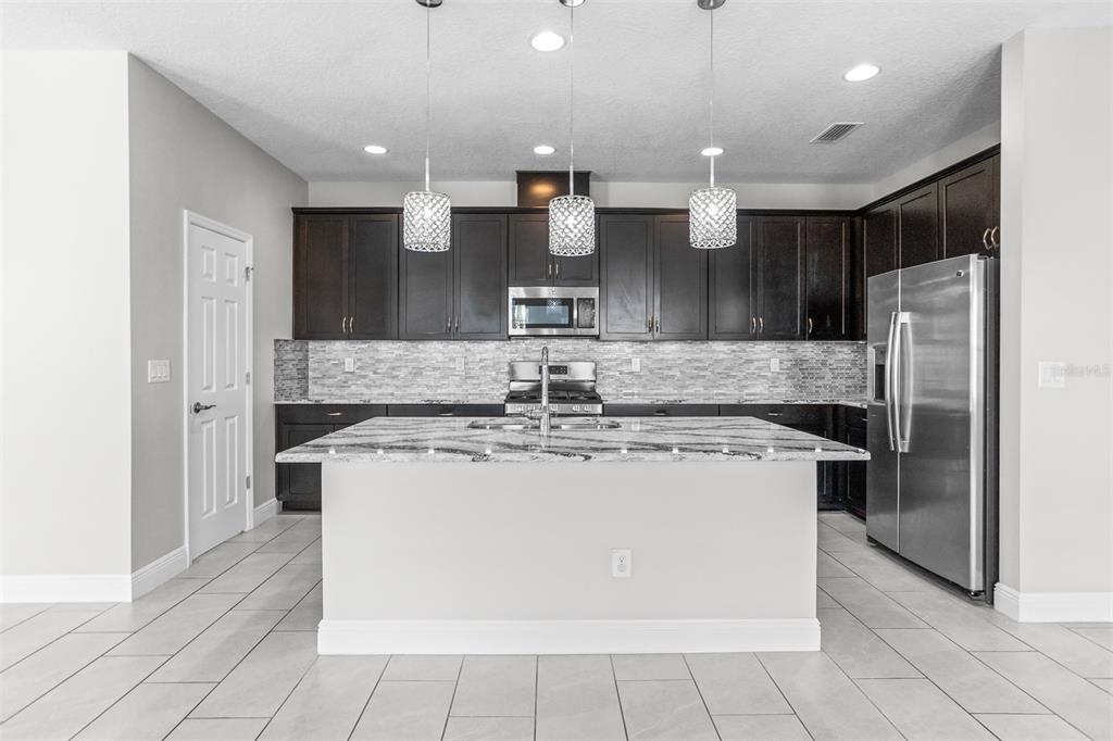 6906 Paradiso Drive Apollo Beach, FL 33572 - Photo 6 of 37 a kitchen with stainless steel appliances granite countertop a sink a stove a refrigerator and cabinets
